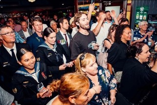 A packed room with hands in the air