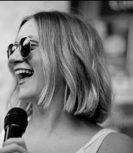 Brydie laughing into a microphone, black and white
